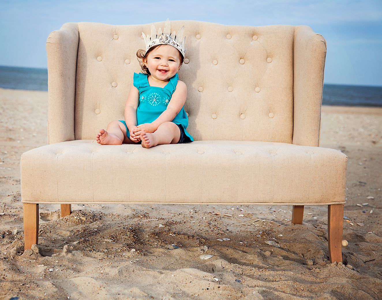 Cute girl with crown sitting on a love seat on the beach in the Outer Banks
