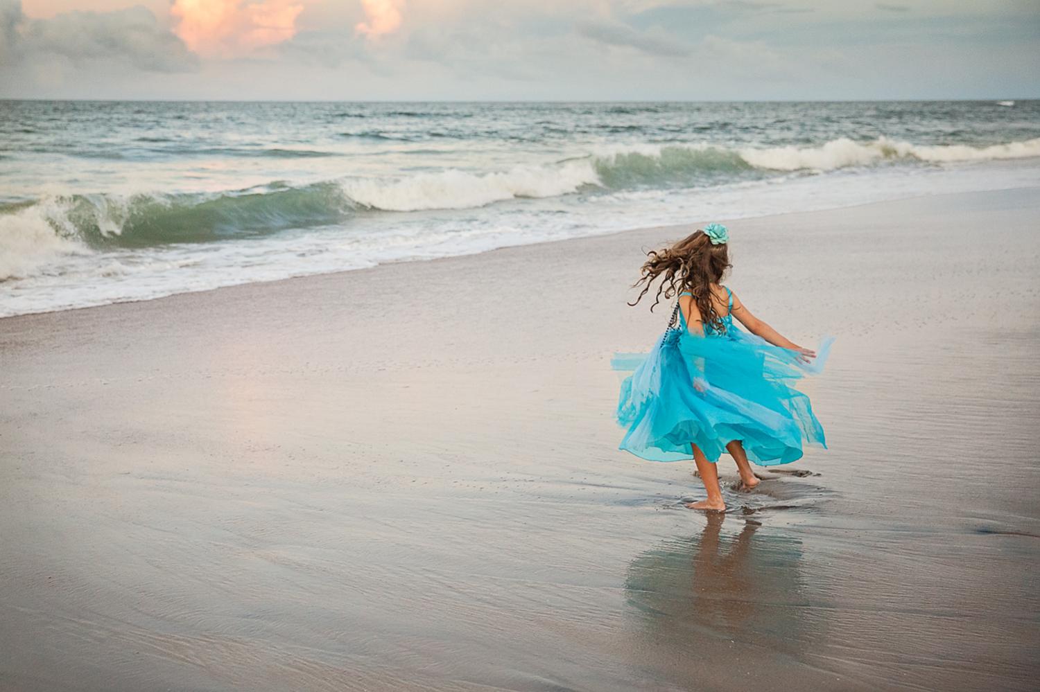 Young girl twirling on the beaches of Nags Head NC